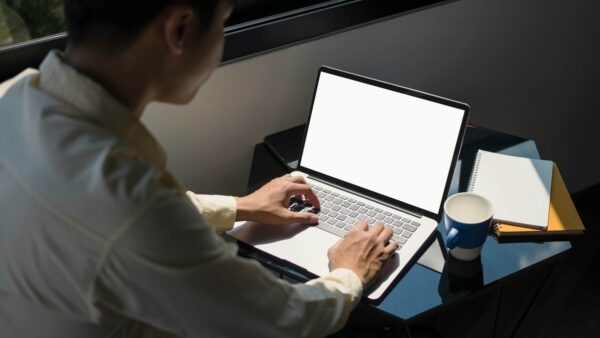 Man on laptop with coffee cup and note pad