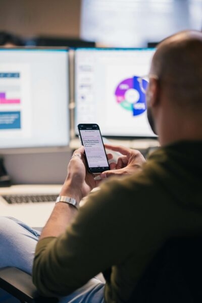 Man on phone with computer screens in background